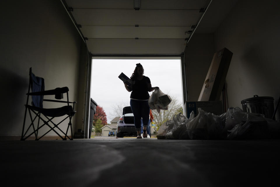 Jesse Johnson of the Family Resource Center carries groceries into client Jodi Ferdinandsen's garage after helping her shop at Walmart and driving her home in Findlay, Ohio, Thursday, Oct. 12, 2023. Earlier this year, Johnson started a job with the Family Resource Center, the same organization that employed the peer support worker who was so instrumental in her own early recovery. (AP Photo/Carolyn Kaster)