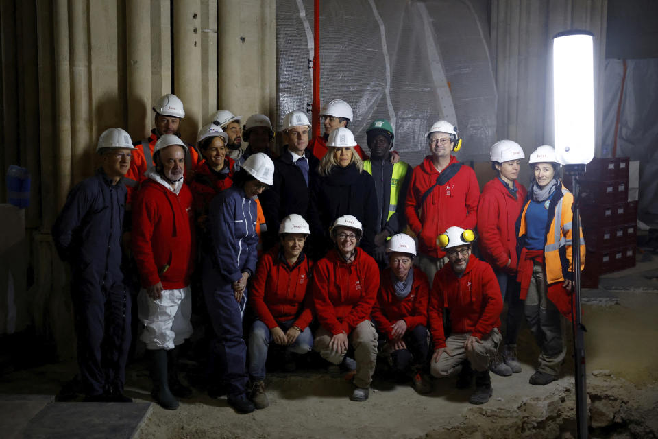 French President Emmanuel Macron and his wife Brigitte Macron, wearing working helmets, pose with archaeologists of INRAP Institute as they visit the nave of Notre Dame de Paris cathedral, Friday, Dec. 8, 2023 in Paris. Emmanuel Macron is visiting Notre Dame Cathedral on Friday, marking the one-year countdown to its reopening in 2024 following extensive restoration after the fire four years ago. (Sarah Meyssonnier, Pool via AP)