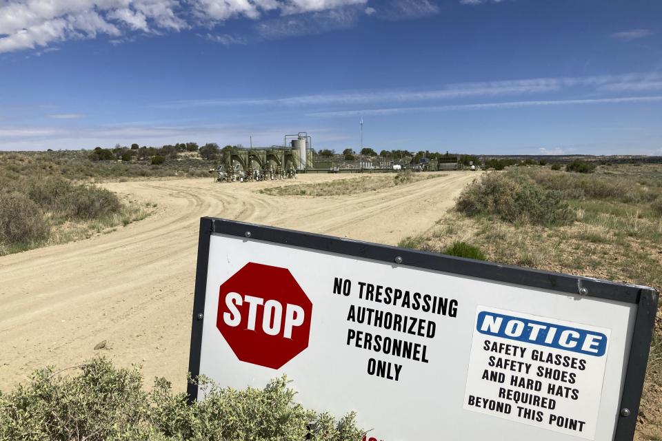 A well site and tanks are located across a highway from a school in Counselor, N.m., on May 17, 2023. On Thursday, June 1, 2023, New Mexico Land Commissioner Stephanie Garcia Richard issued an executive order that includes a ban on all new oil and gas leases on state trust land within a mile (1.6 kilometers) of schools or other educational institutions, including day care centers, preschools and sports facilities that students use. (AP Photo/Susan Montoya Bryan)