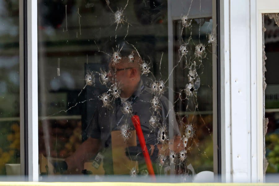 Damage can be seen to a front window law enforcement officers work the scene of a shooting at the Mad Butcher grocery store in Fordyce, Ark., Friday, June 21, 2024. (Colin Murphey/Arkansas Democrat-Gazette via AP)