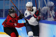 Canada's Mason McTavish (32) and United States' Brock Faber (14) skate behind the net during a preliminary round men's hockey game at the 2022 Winter Olympics, Saturday, Feb. 12, 2022, in Beijing. (AP Photo/Matt Slocum)