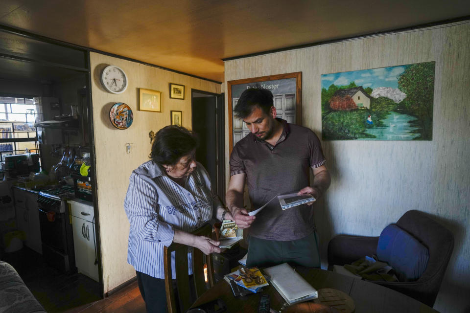 Javier Molina and his mother Maria Cristina Huerta, look at family photos at his home in Santiago, Chile, Friday, Sept. 15, 2023. Molina said he met his abuser, Priest Jorge Laplagne, when he expressed his wish to become a priest, and that the day the priest showed up at his home and told his mother he'd take him to the beach, she felt pressured by fear of losing her job as his secretary at the parish, and agreed. (AP Photo/Esteban Felix)