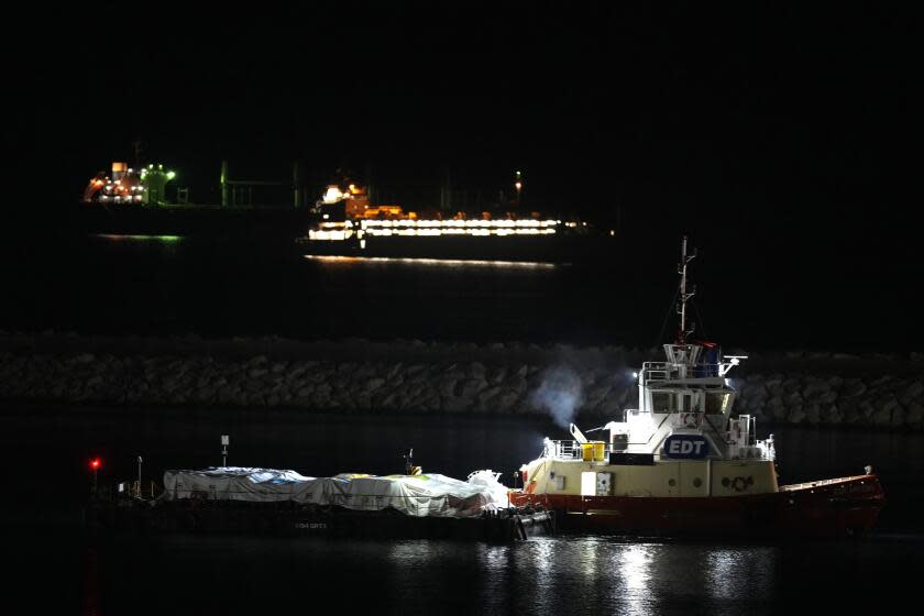 A port marine boat pushs the platform of aid as it prepares to ferry some 200 tons of rice and flour directly to Gaza, at the port in Larnaca, Cyprus, on Sunday, March 10, 2024. The European Commission president said Friday the Open Arms ship will make a pilot voyage as international donors launched a sea corridor to supply the besieged territory that is facing widespread hunger after five months of war. (AP Photo/Petros Karadjias)