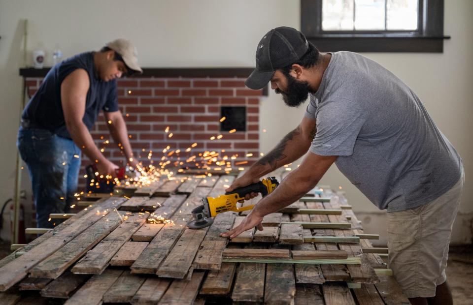 Walker Bonbosa, right, and Regimaldo Reis grind nails down in the original wood flooring at Palm Cottage Thursday, October 20, 2022. They are refurbishing the floor, plank by plank, after the cottage was flooded by Hurricane Ian.