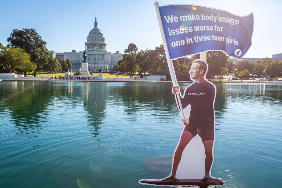 A protest sign outside the U.S. Capitol depicting Facebook CEO Mark Zuckerberg surfing on a wave of cash on Sept. 30, 2021.