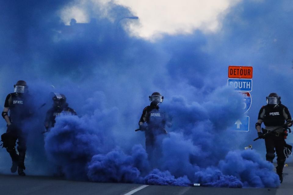 FILE - In this May 30, 2020, file photo, police in riot gear walk through a cloud of blue smoke as they advance on protesters near the Minneapolis 5th Precinct in Minneapolis. Former Minneapolis police Officer Derek Chauvin faces decades in prison when he is sentenced Friday, June 25, 2021, following his murder and manslaughter convictions in the death of George Floyd. Floyd's death, filmed by a teenage bystander as Chauvin pinned Floyd to the pavement for about 9 and a half minutes and ignored Floyd's "I can't breathe" cries until he eventually grew still, reignited a movement against racial injustice that swiftly spread around the world and continues to reverberate.(AP Photo/John Minchillo, File)