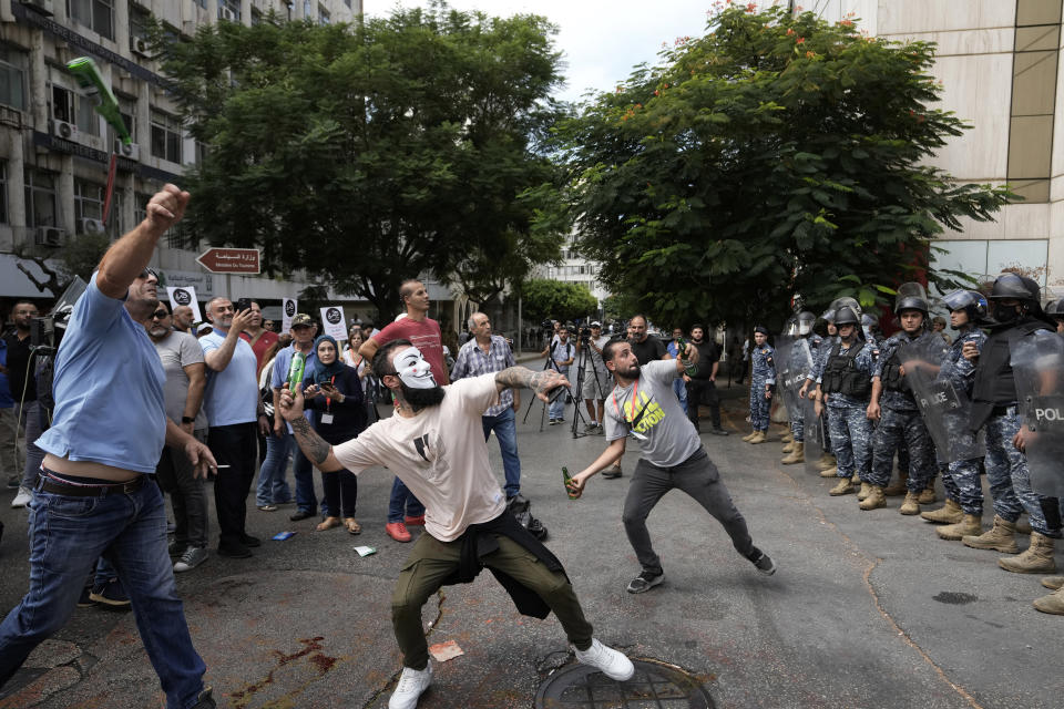 FILE - Protesters throw bottles glasses at the Lebanese Central Bank building, background, where the anti-government demonstrators rally against the Lebanese Central Bank Governor Riad Salameh and the deepening financial crisis, in Beirut, Lebanon, Wednesday, Oct. 5, 2022. Lebanese caretaker Justice Minister Henry Khoury said on Wednesday, Jan. 11, 2023 a European judicial delegation from France, Germany, and Luxembourg have started to arrive in Lebanon as they continue probing Central Bank Governor Riad Salameh and affiliates over corruption allegations. (AP Photo/Hassan Ammar, File)