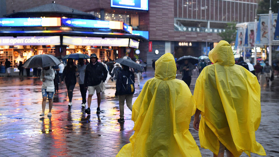 People wearing ponchos, pictured here walking under heavy rain at the US Open. 