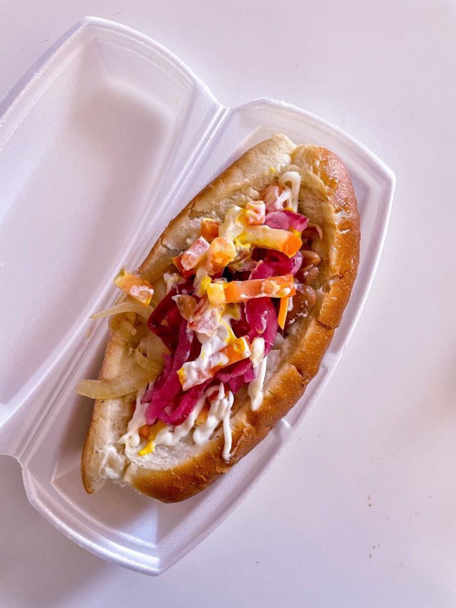 The Sonoran hot dog in a white container on a white table at El Guero Canelo Restaurant, Tucson, slight diagonal