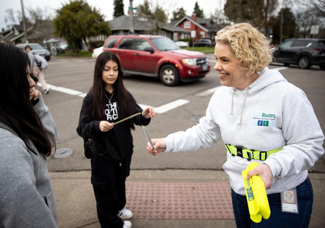Beth Schmidt with Salem-Keizer's Safe Routes to School program pass out safety bracelets to Parrish Middle School students at an intersection where a child was hit by a car earlier this month.
