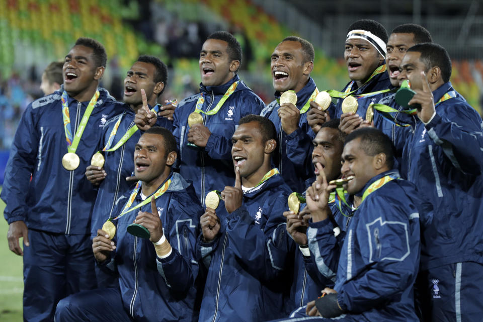 FILE - In this Aug. 11, 2016, file photo, Fiji rugby players show off their gold medal after defeating Britain in the gold medal mens rugby sevens match against Britain at the 2016 Summer Olympics in Rio de Janeiro, Brazil. It was rugby in fast forward and it generated millions of new fans across the world. Rugby sevens made its Olympic debut in Rio de Janeiro in 2016 bringing all the usual hard-hitting tackles, collisions and swerving runs but leaving out the slow-mo elements of the traditional 15-a-side game. (AP Photo/Robert F. Bukaty, File)