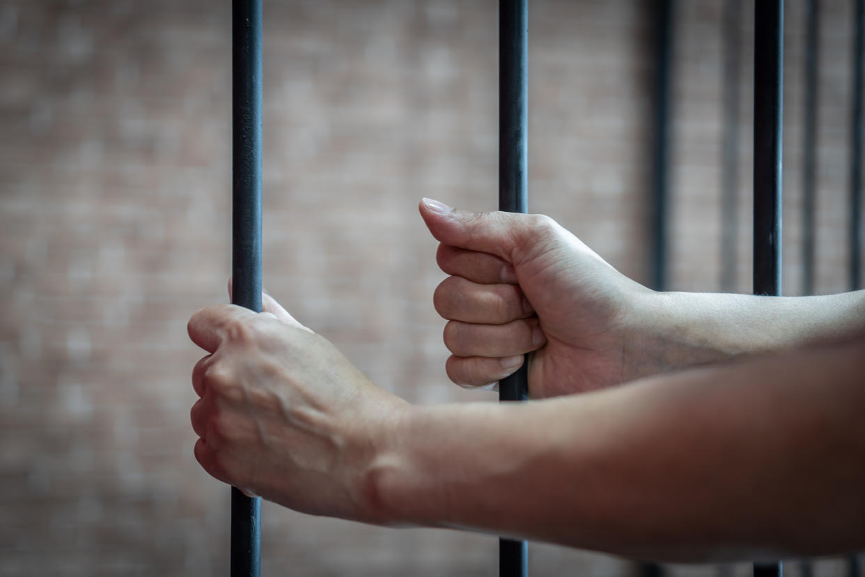 Slavery trade and trafficking victim concept with woman prisoner in jail holding bar being tortured, punished or abused in violation