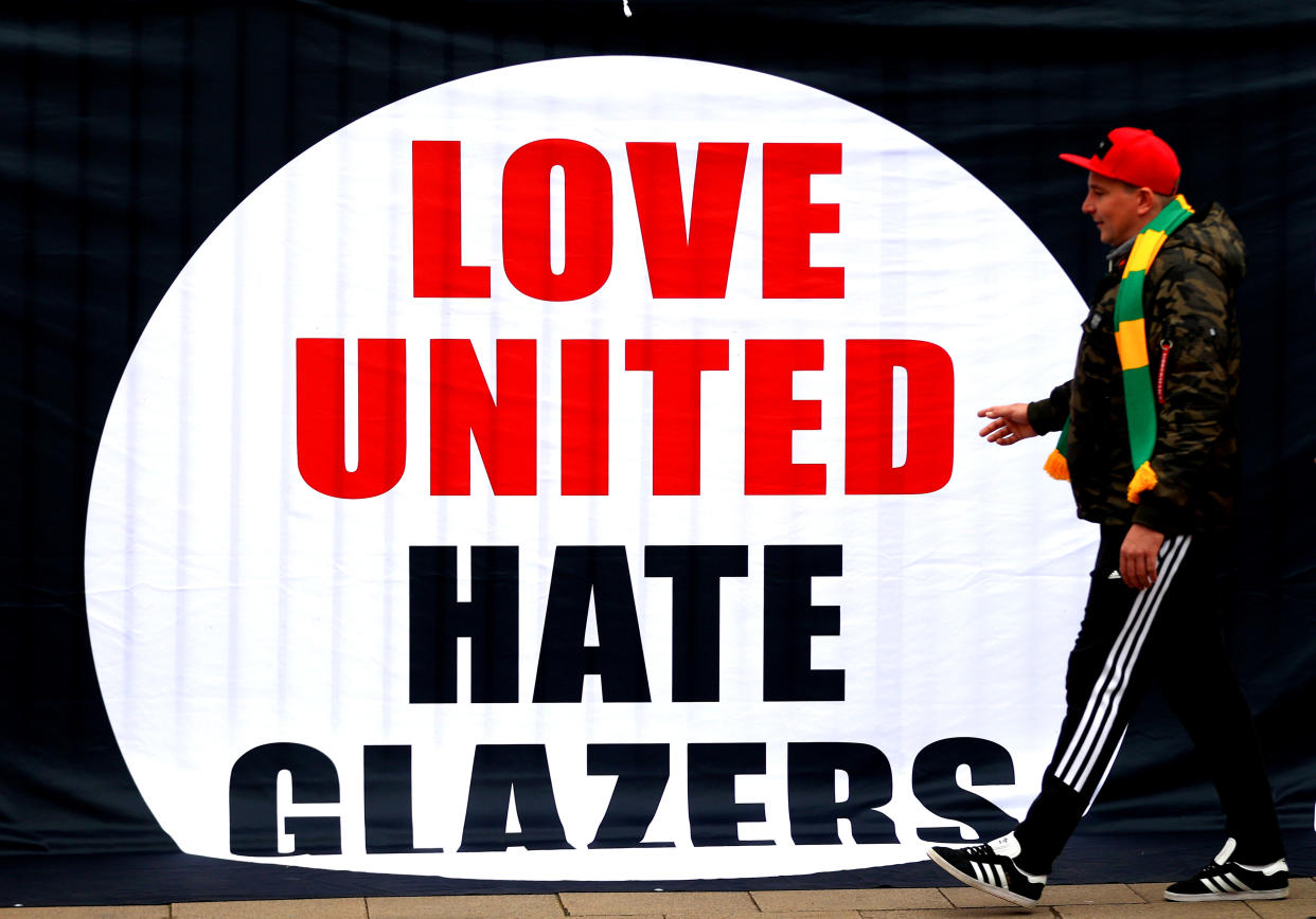 MANCHESTER, ENGLAND - MAY 02: A Manchester United fan walks past a banner saying Love United, Hate Glazers ahead of the Premier League match between Manchester United and Brentford at Old Trafford on May 02, 2022 in Manchester, England. (Photo by Catherine Ivill/Getty Images)