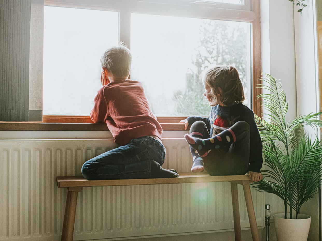 Young Girl and Boy sit on a Bench by a Sunny Window and Gaze out