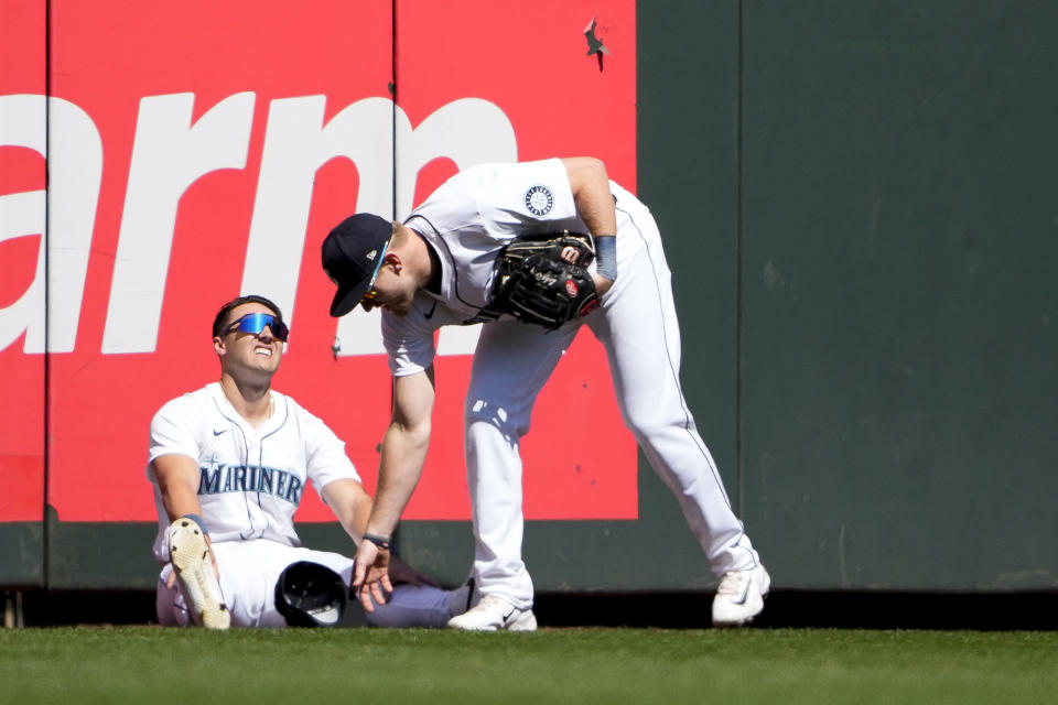 Seattle Mariners center fielder Luke Raley, right, checks on left fielder Dominic Canzone, left, after Canzone collided with the wall while catching a fly ball hit by Chicago Cubs' Mike Tauchman during the second inning of a baseball game, Sunday, April 14, 2024, in Seattle. Canzone left the game due to injury after the play. (AP Photo/Lindsey Wasson)