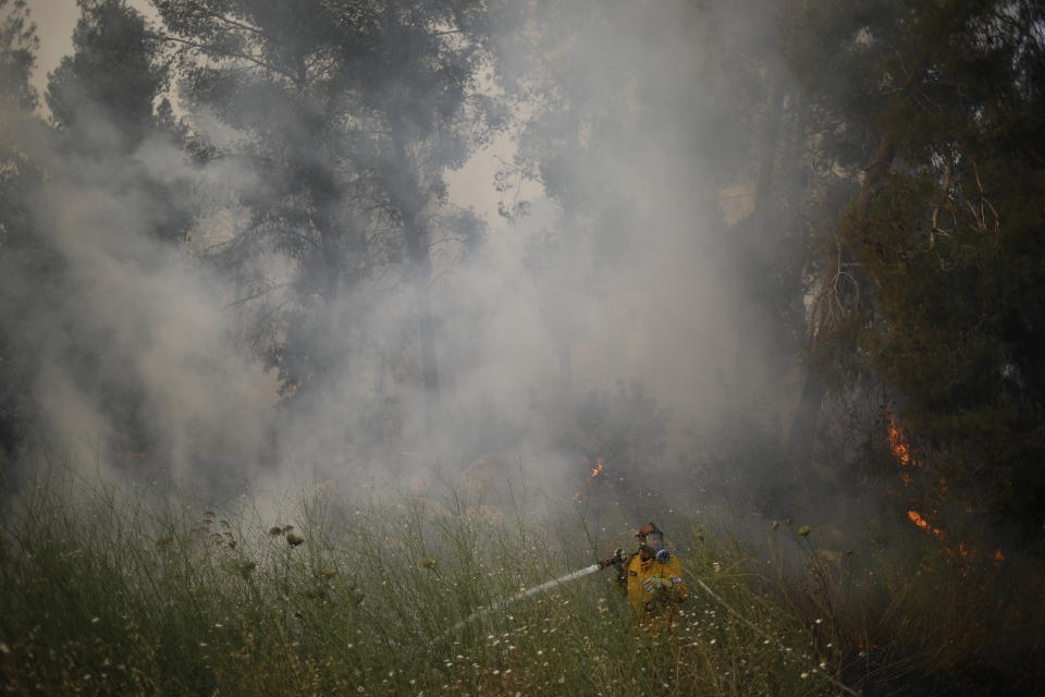 Fire fighters extinguish a forests fire near Kfar Uriya, Thursday, May 23, 2019. Israeli police have ordered the evacuation of several communities in southern and central Israel as wildfires rage amid a major heatwave. (AP Photo/Ariel Schalit)