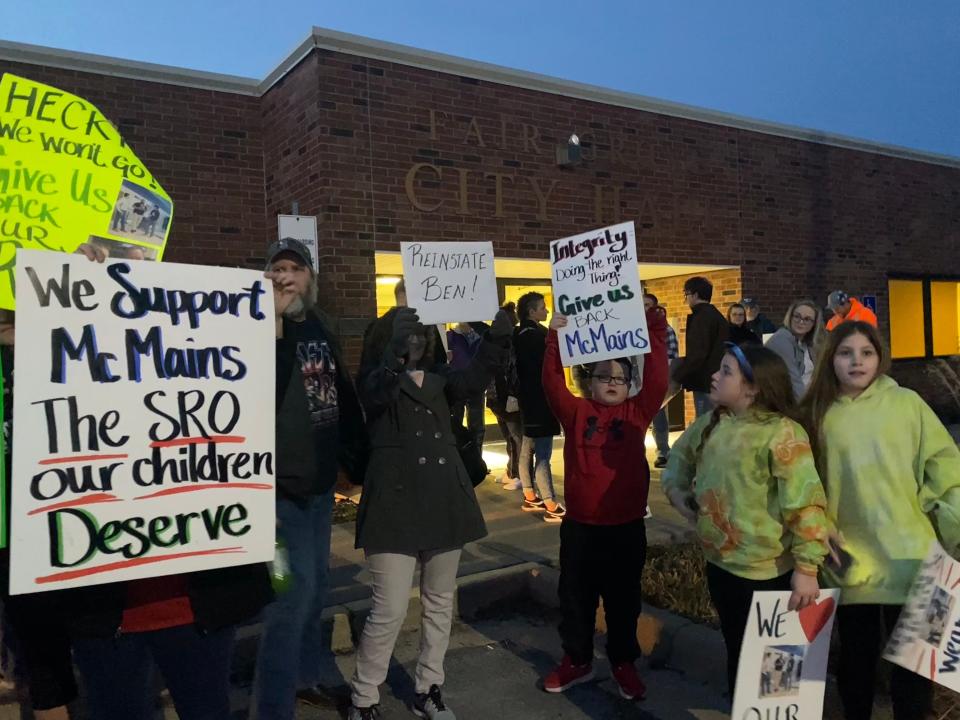 Fair Grove residents hold up signs in support of Ben McMains in front of Fair Grove City Hall on Tuesday, Feb. 6, 2024. People gathered to show their support of McMains's appeal to remain as the school resource officer.