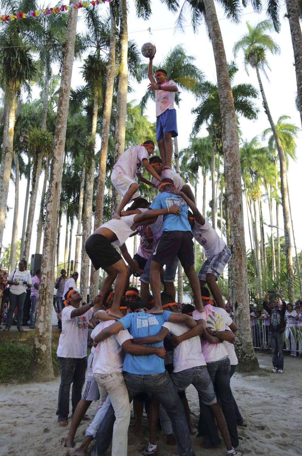Surinamese men of mixed ethnic origins compete in the Indian folk sport called Makhan Chor (butter thief) during the Hindu Festival of Holi, known as the Festival of Colors, in Paramaribo, Suriname, March 17, 2014. Makhan Chor is played by forming a human pyramid with the lightest on top trying to grab a jar of butter hanging some 6 to 7 meters high. Makhan Chor is also one of the many names of the Hindu Lord Krishna who steals butter with his friends. REUTERS/Ranu Abhelakh (SURINAME - Tags: RELIGION SOCIETY)