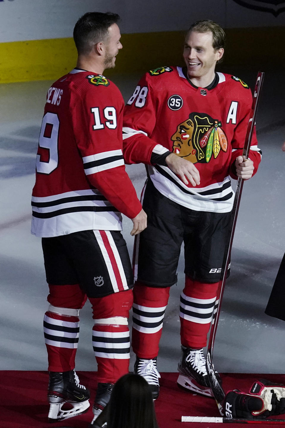 Chicago Blackhawks right wing Patrick Kane, right, smiles as he is joined by center Jonathan Toews while being honored for his 1,000th career NHL hockey game, which happened in March, before the team's game against the Vancouver Canucks in Chicago, Thursday, Oct. 21, 2021. (AP Photo/Nam Y. Huh)