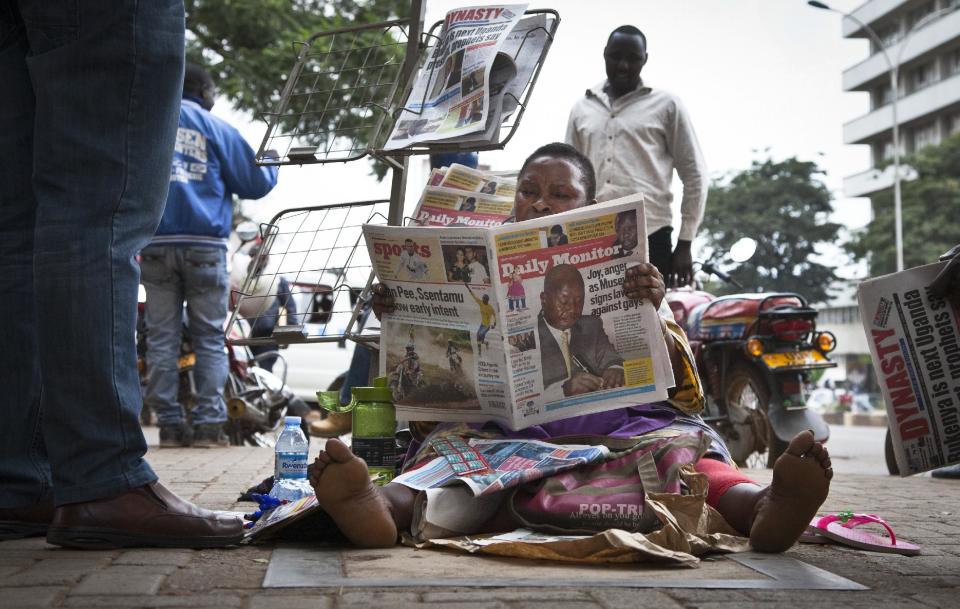 A Ugandan newspaper seller reads a copy of the "Daily Monitor" newspaper on the street in Kampala, Uganda Tuesday, Feb. 25, 2014. The Ugandan "Red Pepper" tabloid newspaper published a list Tuesday of what it called the country's "200 top" homosexuals, outing some Ugandans who previously had not identified themselves as gay, one day after the president Yoweri Museveni enacted a harsh anti-gay law. (AP Photo/Rebecca Vassie)