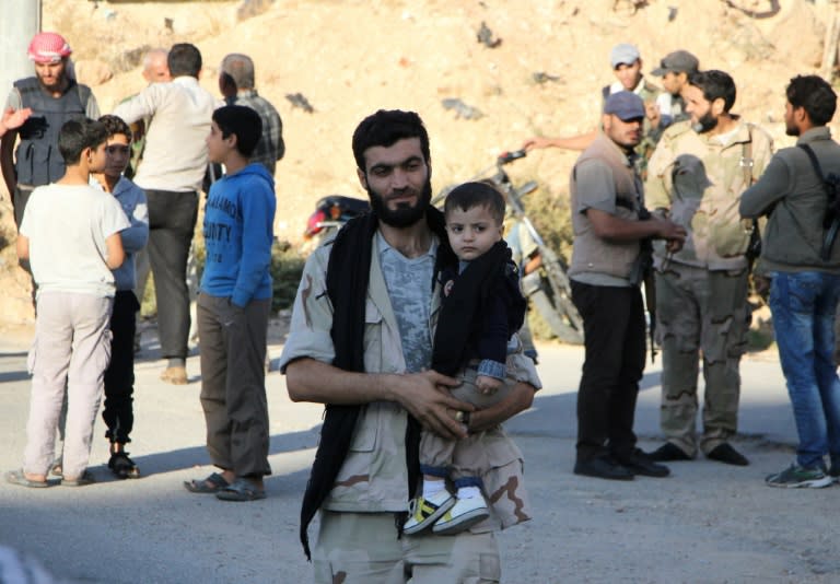 Syrian rebel fighters and their families arrive on the outskirts of Idlib, bordering the Hama province, following their evacuation from a besieged town on October 20, 2016