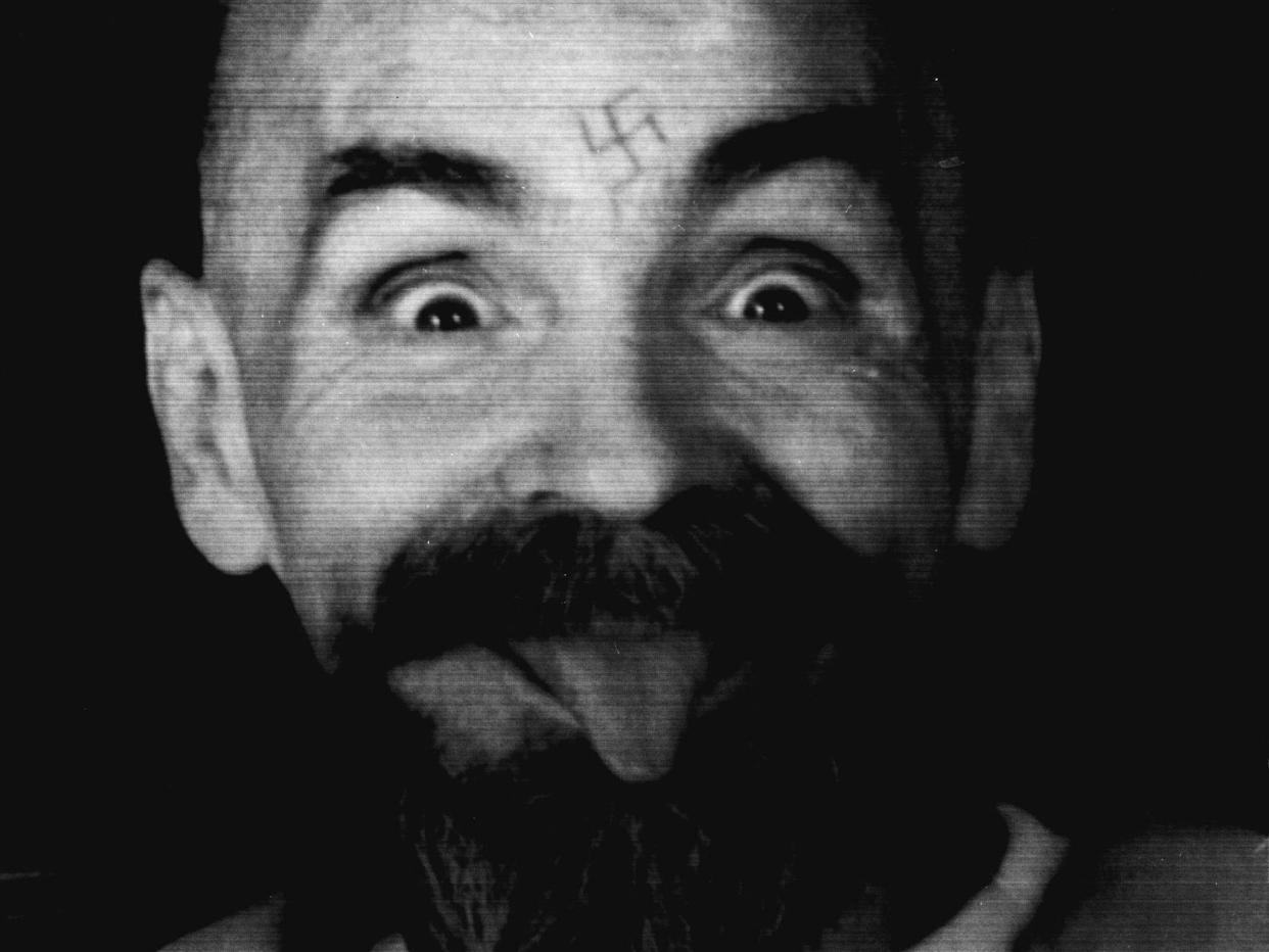 Charles Manson clowns around as he is led to his cell in 1989: Reuters