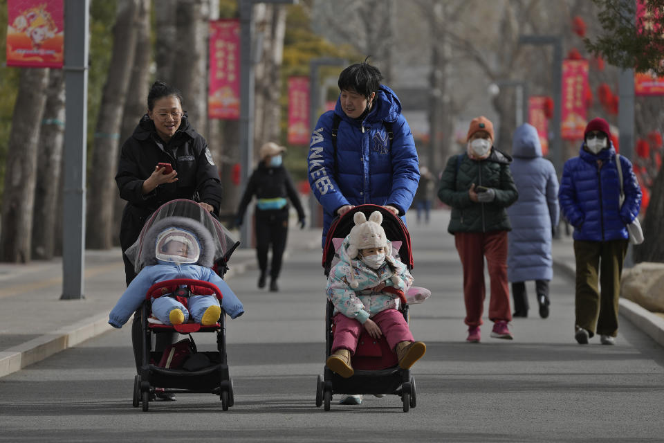 Women walk with their toddlers as residents visit a public park in Beijing, Thursday, Jan. 19, 2023. China on Thursday accused "some Western media" of bias, smears and political manipulation in their coverage of China's abrupt ending of its strict "zero-COVID" policy, as it issued a vigorous defense of actions taken to prepare for the change of strategy. (AP Photo/Andy Wong)
