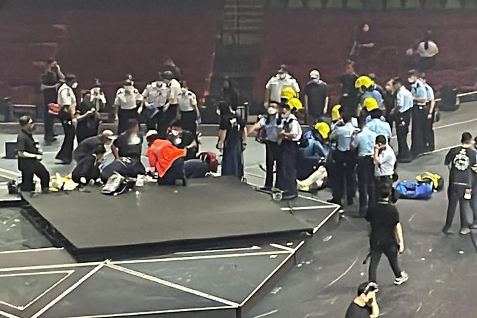 This handout photo courtesy of an anonymous source taken on July 28, 2022 and received on July 29 shows paramedics (front L and R) treating two dancers on stage after an overhead video screen fell during a concert by boy band Mirror at the Hong Kong Coliseum in Hong Kong. - At least two Hong Kong dancers were injured on July 28 after being hit by a falling screen at a concert of the city's most popular boy band Mirror.