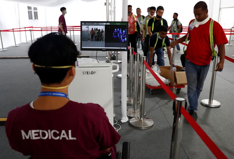 Contractors and workers pass a thermal scanner as part of the coronavirus outbreak precautions during a media preview of the Singapore Airshow in Singapore