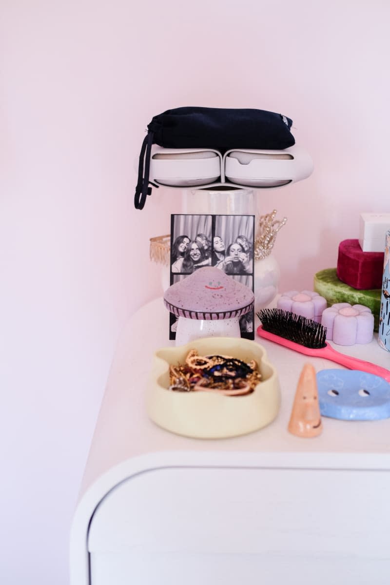 Dish holds jewelry on white dresser in pink bedroom.