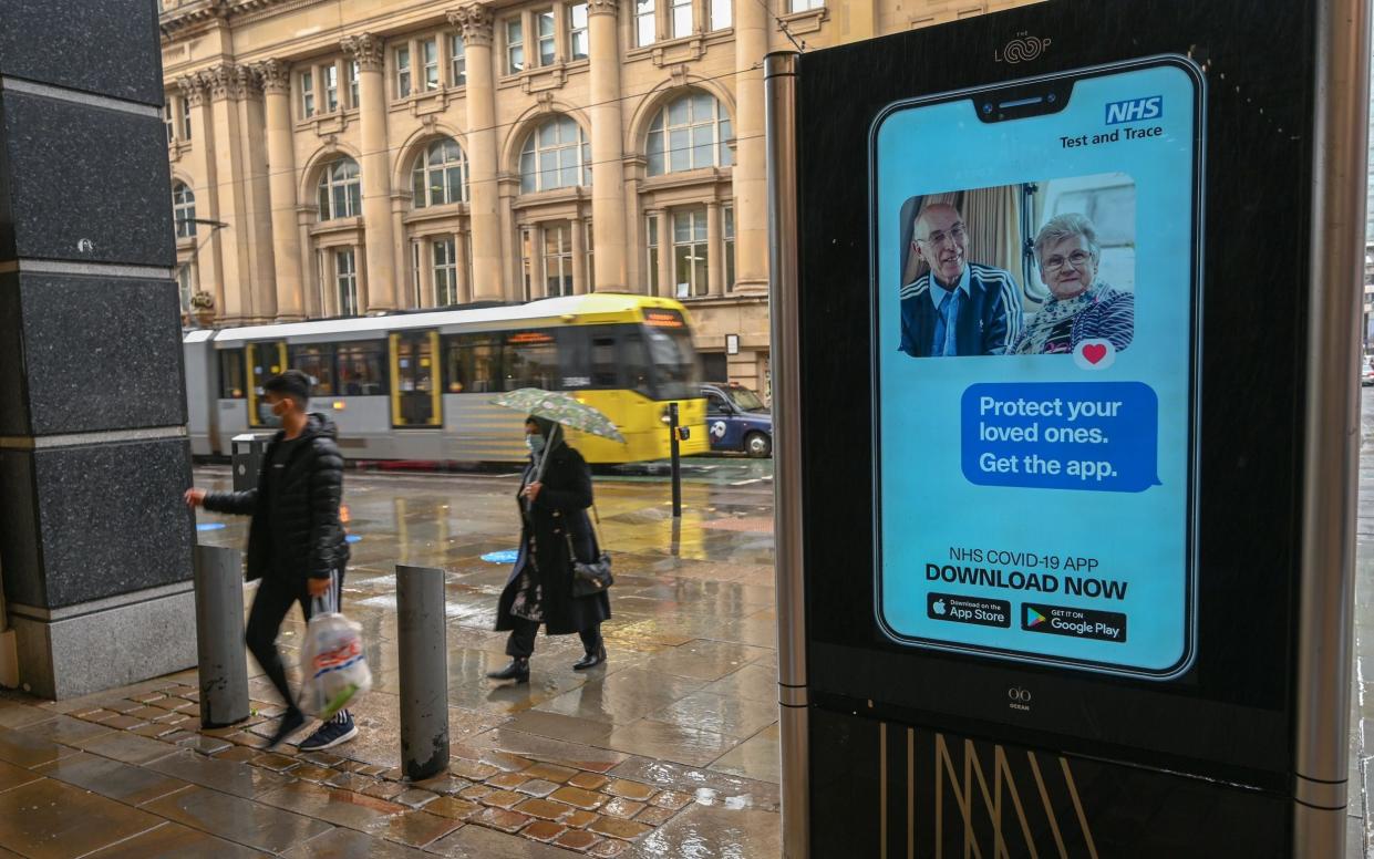 People walk past an electronic sign reminding pedestrians to download the NHS Test and Trace app in Manchester - Paul Ellis/AFP