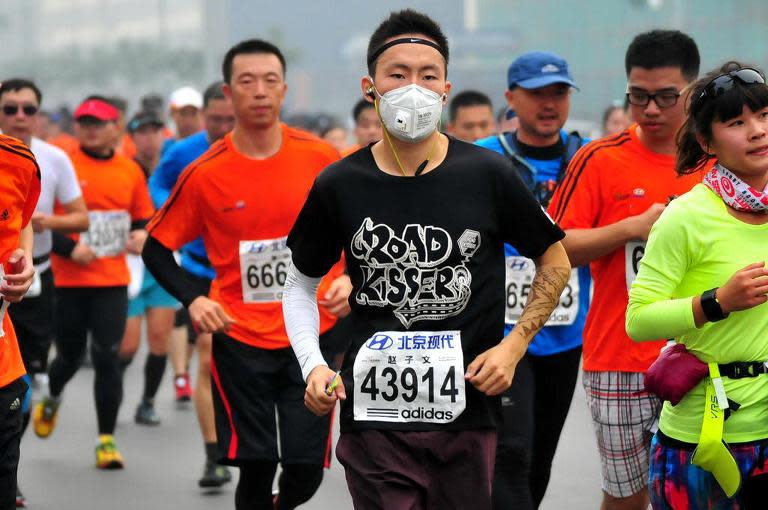 A runner wears a mask as he takes part in the 34th Beijing International Marathon which began at Tiananmen Square in Beijing on October 19, 2014