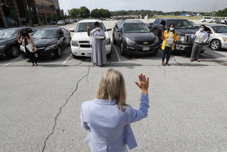La empleada del servicio de inmigración Penny Luthens le toma juramento a varios inmigrantes durante una ceremonia de naturalización realizada en un estacionamiento de Des Moines, Iowa, el 26 de junio del 2020. (AP Photo/Charlie Neibergall)