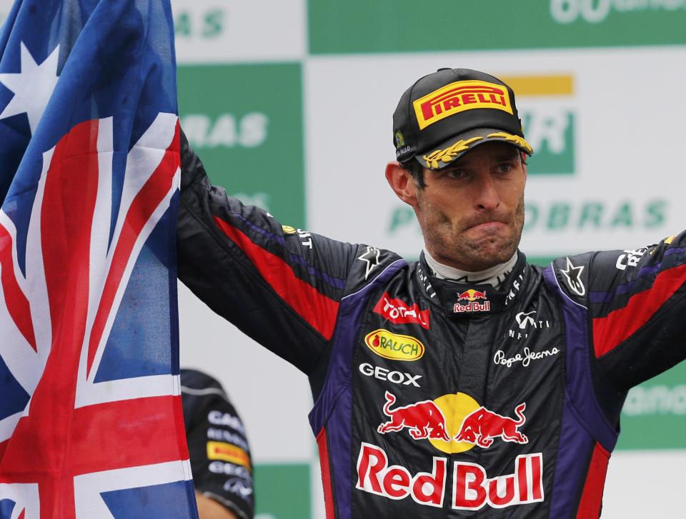 Mark Webber of Australia acknowledges the crowd as he holds up the Australian flag during podium celebrations after the Brazilian F1 Grand Prix at the Interlagos circuit in Sao Paulo