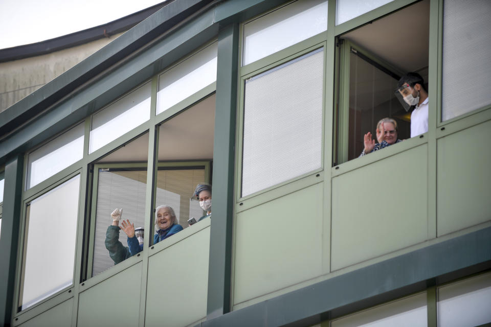 Hospice personnel and residents applaud from a window of the elderly people's home to a Russian team who sanitized the structure to contain the spread of the Covid-19 virus, in Albino, near Bergamo, northern Italy, Saturday, March 28, 2020. The new coronavirus causes mild or moderate symptoms for most people, but for some, especially older adults and people with existing health problems, it can cause more severe illness or death. (Claudio Furlan/LaPresse via AP)