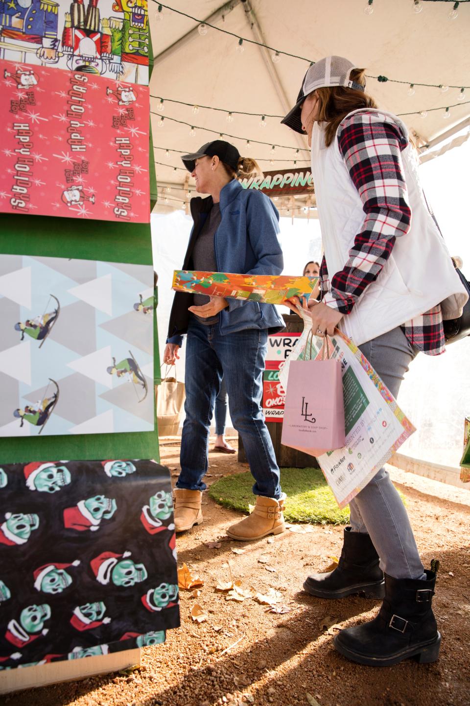 Two women shop for gift wrap designed by local artists at The Curbside Chronicle booth at the Midtown Holiday Pop-Up Shops. [Photo provided by Nathan Poppe]
