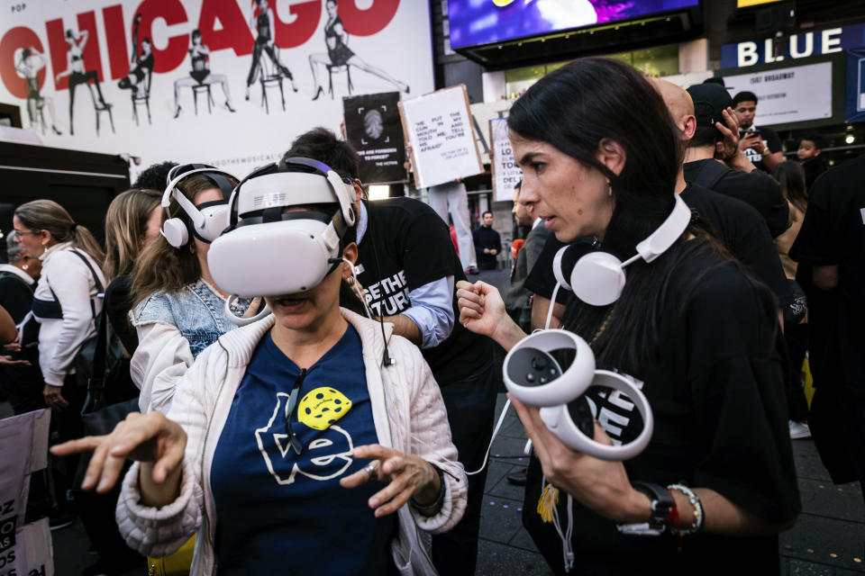 People standing near Times Square wear VR headsets screening an immersive experience of the conditions at El Helicoide, a government detention center for political prisoners in Venezuela, on Tuesday, Sept. 19, 2023, in New York. Protesters gathered to demand the closure of the center over allegations of torture and the release of political prisoners in Venezuela. (AP Photo/Stefan Jeremiah)