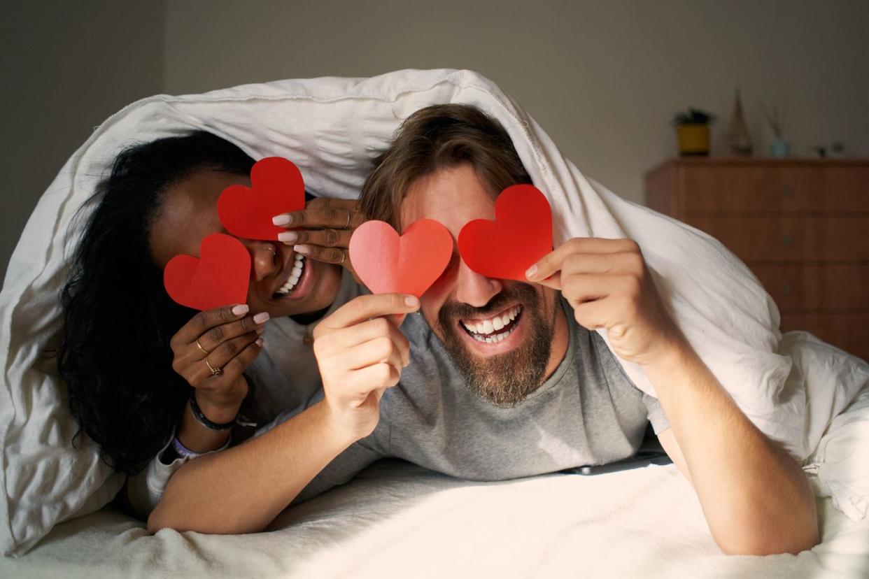 young couple making heart eyes in bed together