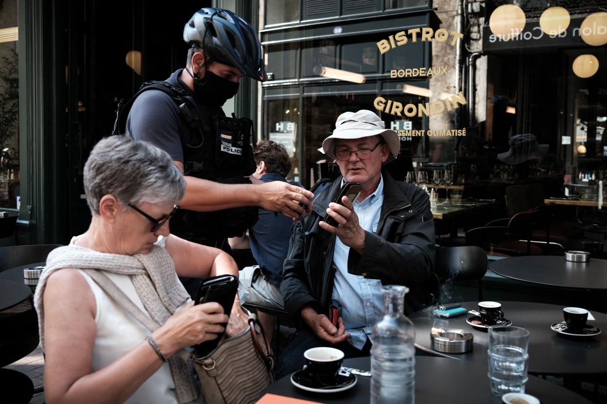 A policeman checks the health pass of a customer at a bar in Bordeaux, southwestern France, on Aug. 11, 2021. People in France must now show a health pass to order a coffee in a cafe or travel on intercity trains as the French President's controversial plan to squeeze infections and encourage vaccination came into full effect.