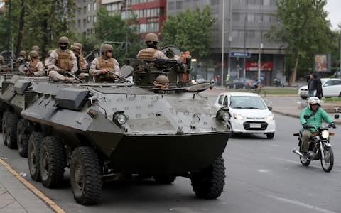 Soldiers ride an armoured transporter as they patrol Santiago  - Credit: REUTERS/Ivan Alvarado