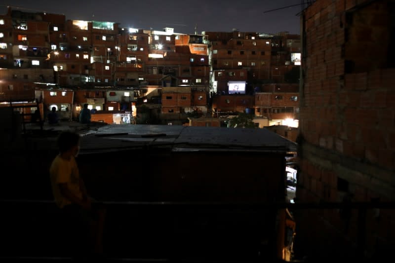 A boy watches a movie projected on a giant screen in the low-income neighborhood of Petare, amid the coronavirus disease (COVID-19) outbreak in Caracas