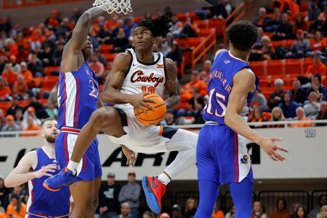 Oklahoma State Cowboys guard Javon Small (12) goes to the basket between Kansas Jayhawks forward K.J. Adams Jr. (24) and guard Kevin McCullar Jr. (15) during a college basketball game between the Oklahoma State University Cowboys (OSU) and the Kansas Jayhawks at Gallagher-Iba Arena in Stillwater, Okla., Tuesday, Jan. 16, 2024. Kansas won 90-66.