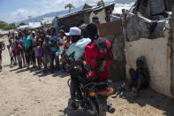 G9 coalition gang members ride a motorcycle through the Wharf Jeremy street market in Port-au-Prince, Haiti, Wednesday, Oct. 6, 2021. While some gangs have turned to kidnapping, like those who captured 17 missionaries and their relatives, Jimmy Cherizier, aka Barbecue, a former policeman who leads the G9 gang coalition, has taken control of the port district, gaining a stranglehold on the country's economy. (AP Photo/Rodrigo Abd)