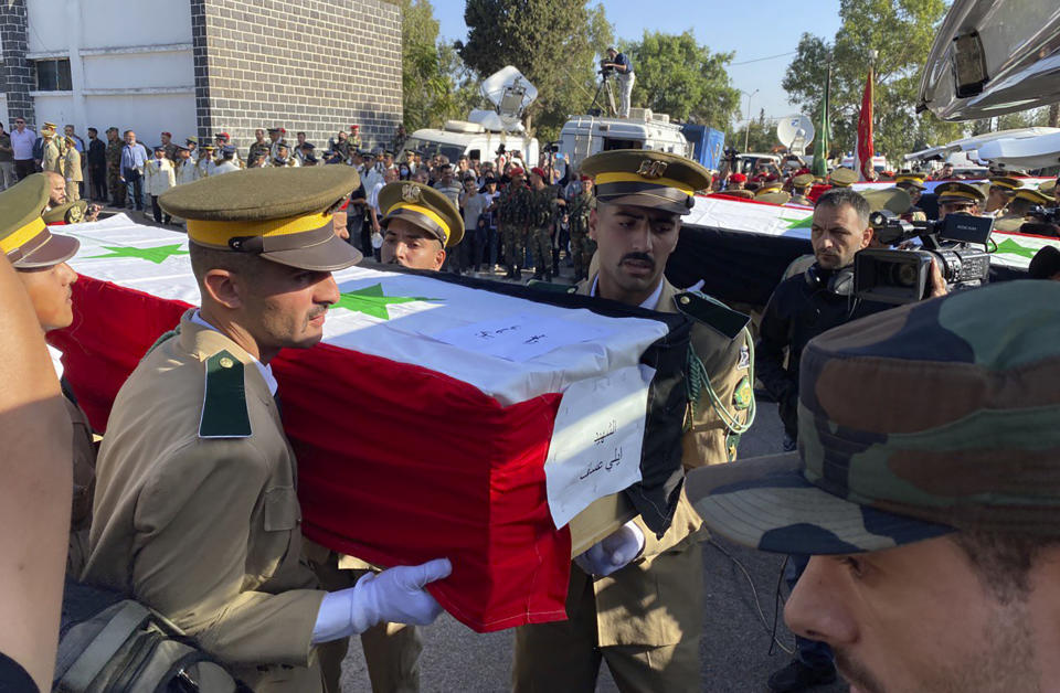 Syrian student officers carry the coffins of a victim who were killed on Thursday in a drone attack that hit a military graduation ceremony, during a mass funeral procession in Homs, Syria, Friday, Oct. 6, 2023. Family members of some of the victims of deadly drone attacks on a crowded military graduation that killed scores gathered outside a military hospital in this central city Friday to collect the bodies of their loved ones who lost their lives in one of Syria's deadliest single attacks in years. (AP Photo/Albert Aji)