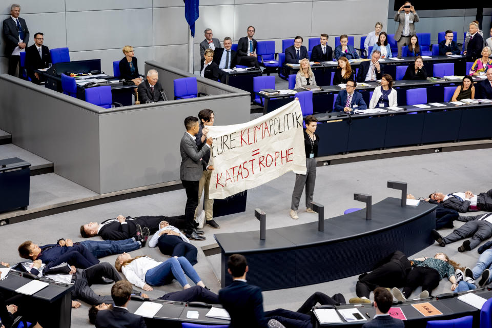 Participants of a protest action for climate justice by Fridays For Future hold a banner reading 'your climate politics means catastrophe" in the plenary hall of the Bundestag in Berlin, Germany, Tuesday, June 4, 2019. In the simulation game "Youth and Parliament", young people slip into the role of members of the Bundestag. (Christoph Soeder/dpa via AP)