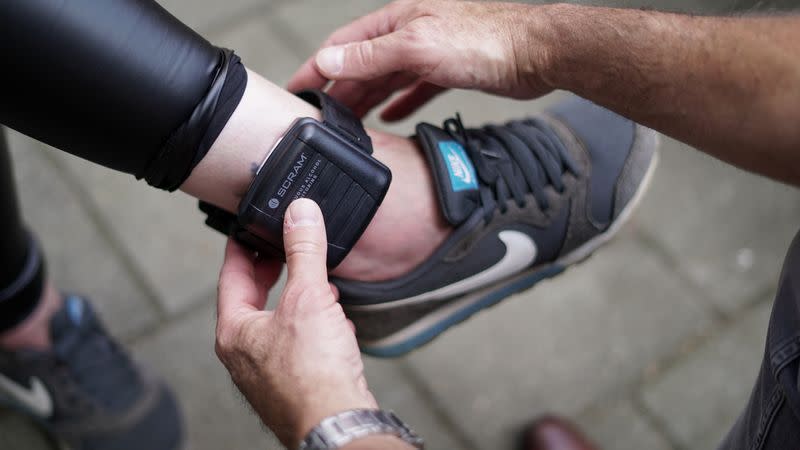 Probation officer Tony Rubino adjusts an ankle strap called "alcoholmeter" in Zutphen