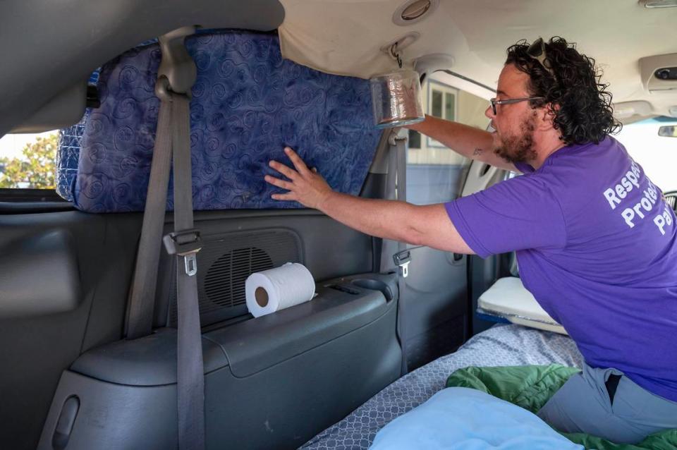 Mel Vezina places window covers they made for sleeping in their van while getting ready to leave Sunday for the week to work in Fremont. “I made a big sacrifice for the students,” Vezina said. “But I struggle with not being able to go home to regroup myself.”
