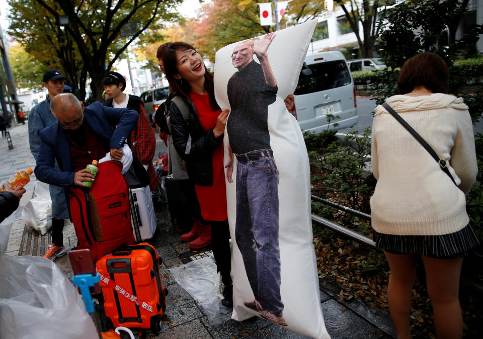 Ayano Tominaga poses with a cushion printed with a portrait of Apple co-founder Steve Jobs on it, as she waits in queue for the release of Apple’s new iPhone X in front of the Apple Store in Tokyo’s Omotesando shopping district