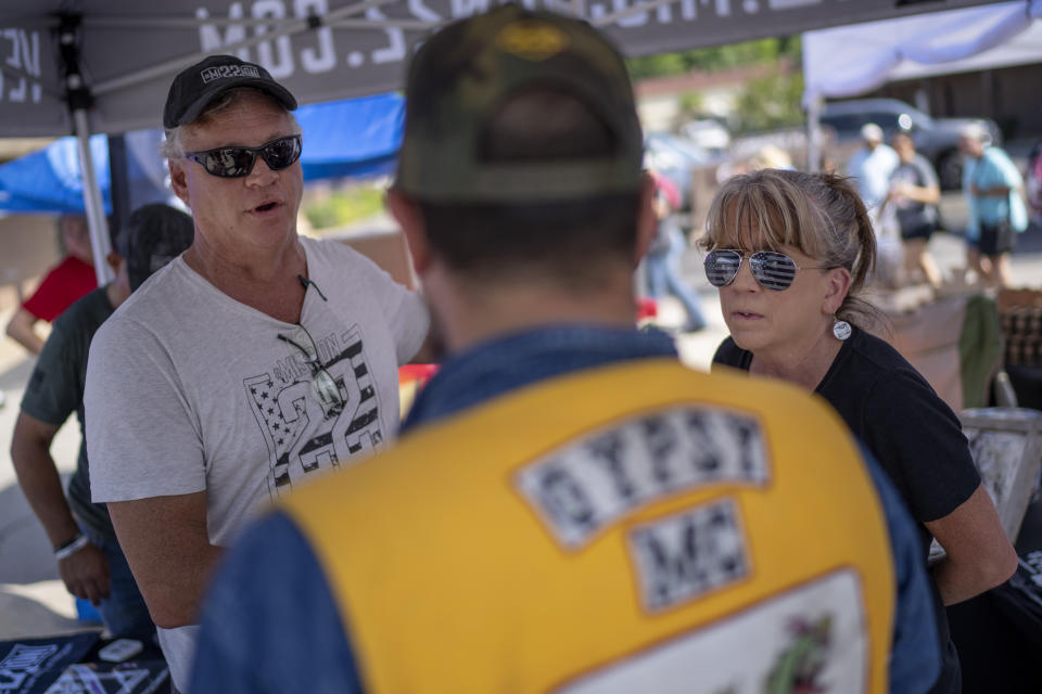 Robert and Barbie Rohde talk with a veteran at a festival while volunteering for Mission 22, a nonprofit that is focused on ending military and veteran suicide, Saturday, June 10, 2023, in Jacksonville, Texas. Experts say that traumatic experiences at war play a role in service members having a suicide rate nearly twice as high as others. Yet even those with no combat history die by suicide at a much higher rate. What they have in common, researchers say, is demographics that are especially vulnerable to suicide: predominately white men with access to and a familiarity with firearms. (AP Photo/David Goldman)