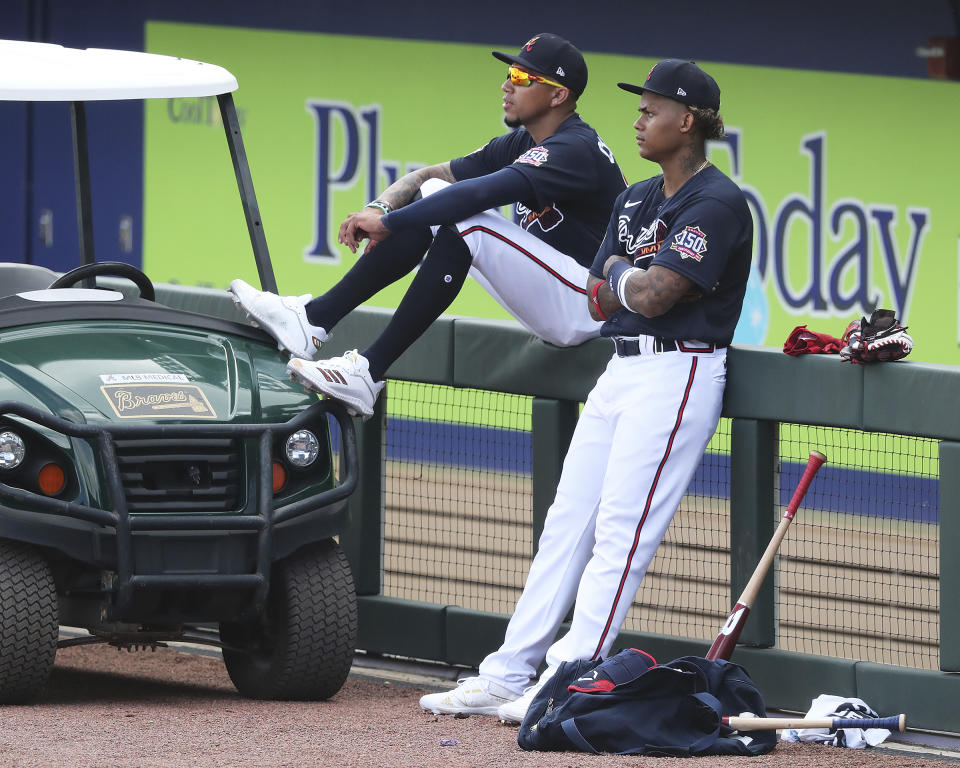 Atlanta Braves infielder Johan Camargo, left, and outfielder Cristian Pache watch spring training baseball practice in North Port, Fla., Wednesday, Feb. 24, 2021. (Curtis Compton/Atlanta Journal-Constitution via AP)